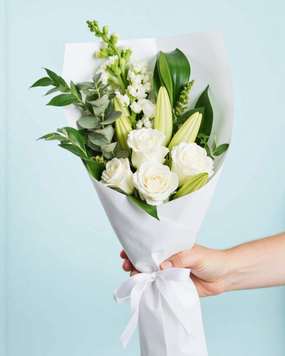 small, white flower bouquet with white roses, lilies and greenery.