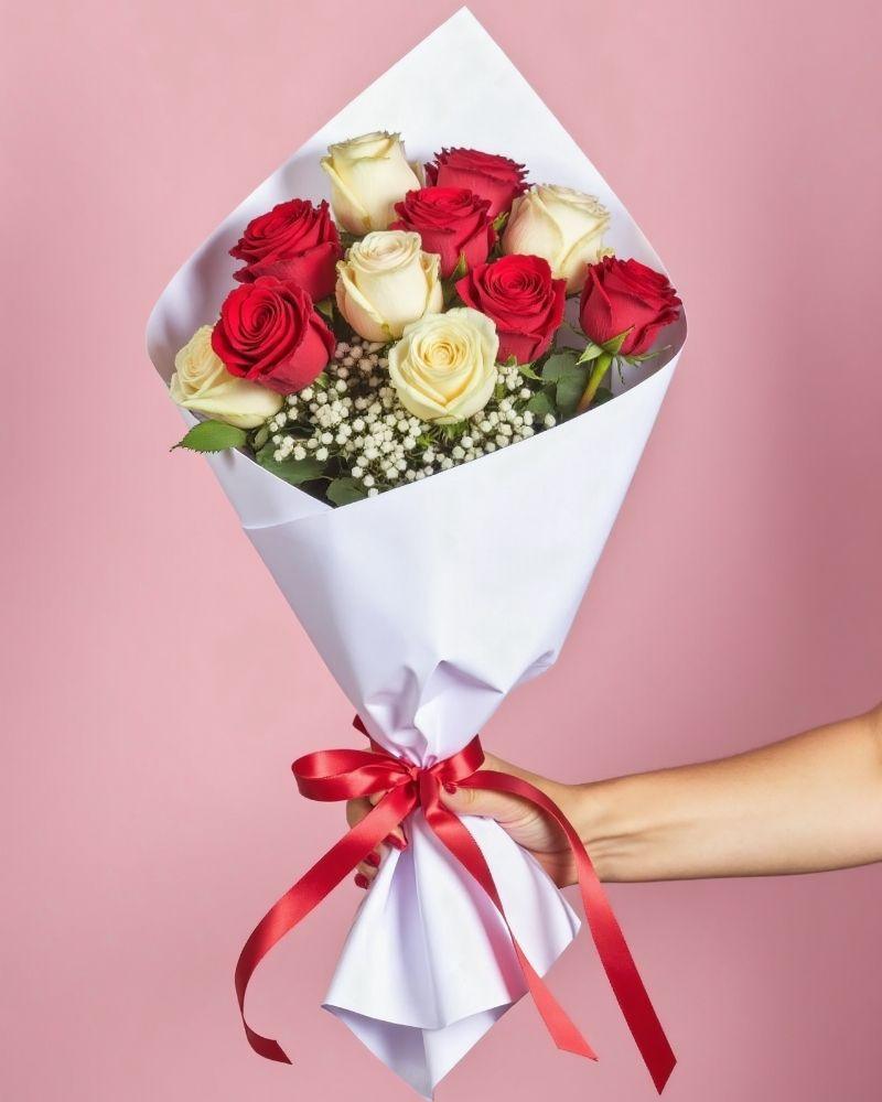 Fire & Ice - Roses Bouquet featuring a mix of red and white roses with baby's breath. The bouquet is wrapped in white tissue paper and a red ribbon.