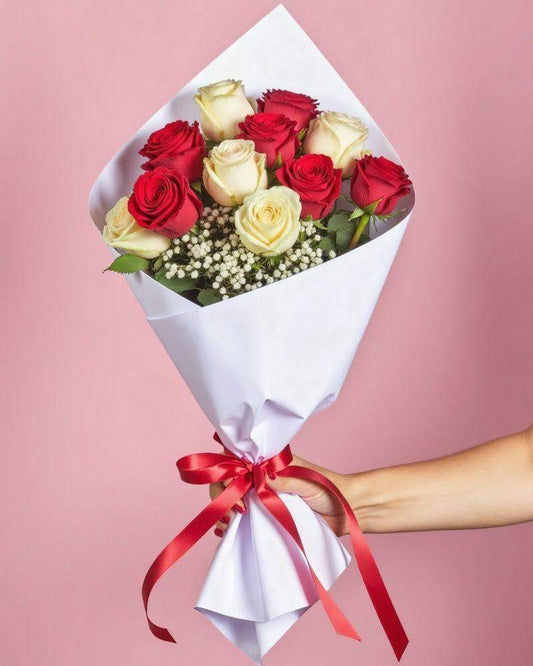 Fire & Ice - Roses Bouquet featuring a mix of red and white roses with baby's breath. The bouquet is wrapped in white tissue paper and a red ribbon.